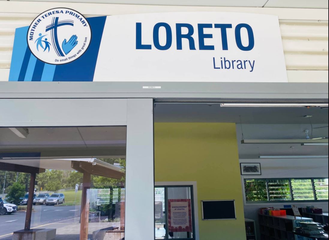Sign above a glass doorway reading “Loreto Library,” with the Mother Teresa Primary School logo displayed beside it.